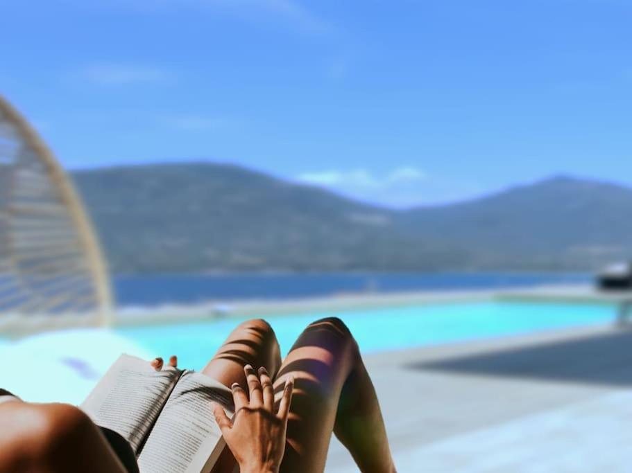 une femme qui pose un livre à côté d'une piscine dans l'établissement Casa di l'Alivi - Villa avec vue exceptionnelle, à Propriano