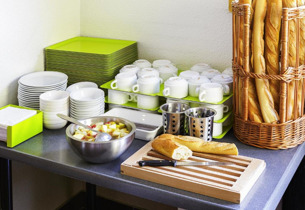 a table with plates and a bowl of food and bread at ibis budget Chartres in Chartres