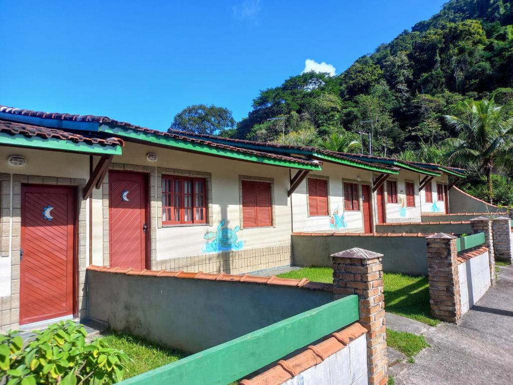 a row of houses with red doors and a mountain at Chalés Luz Da Lua in Caraguatatuba