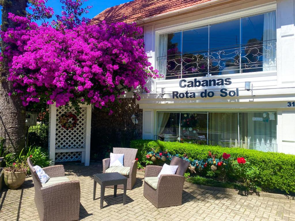 a group of chairs and flowers in front of a building at Pousada Cabanas Rota do Sol in Gramado