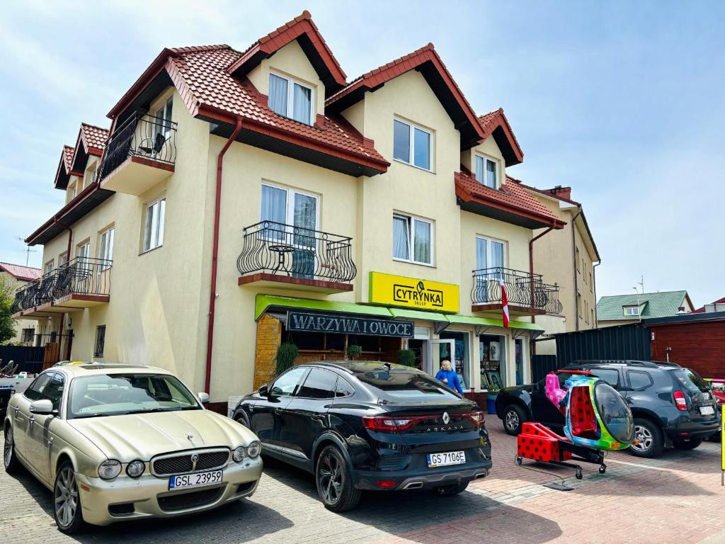two cars parked in a parking lot in front of a building at Sztorm Rowy in Rowy