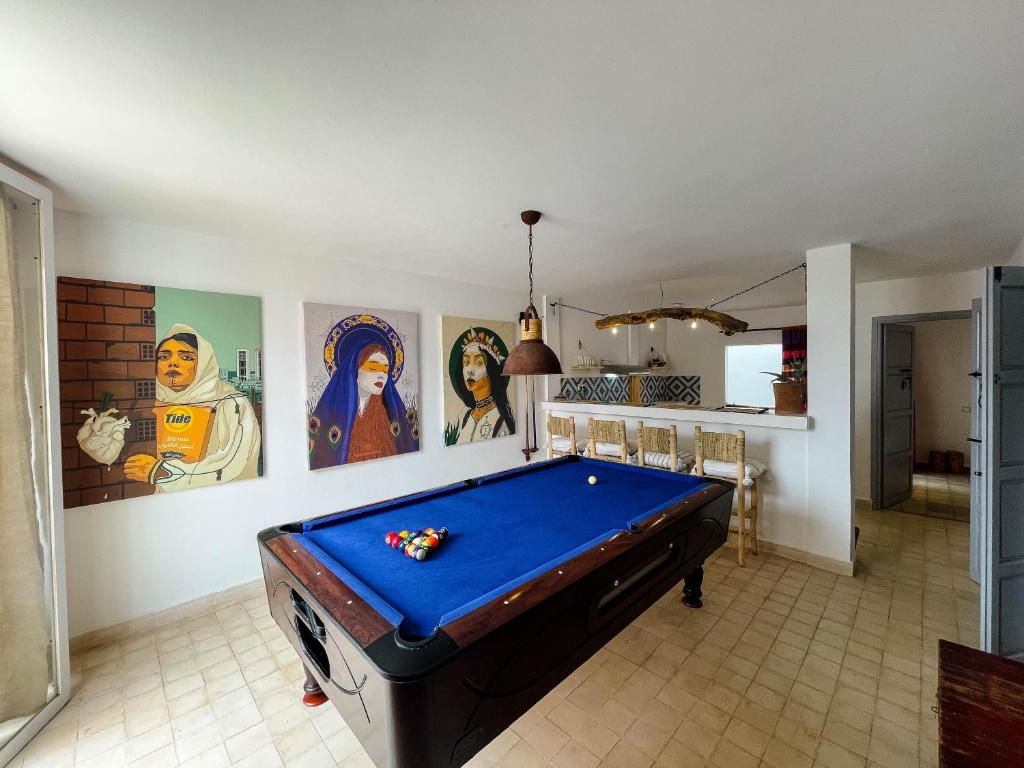 a pool table in a room with paintings on the walls at Taouarguit Guest House in Imsouane