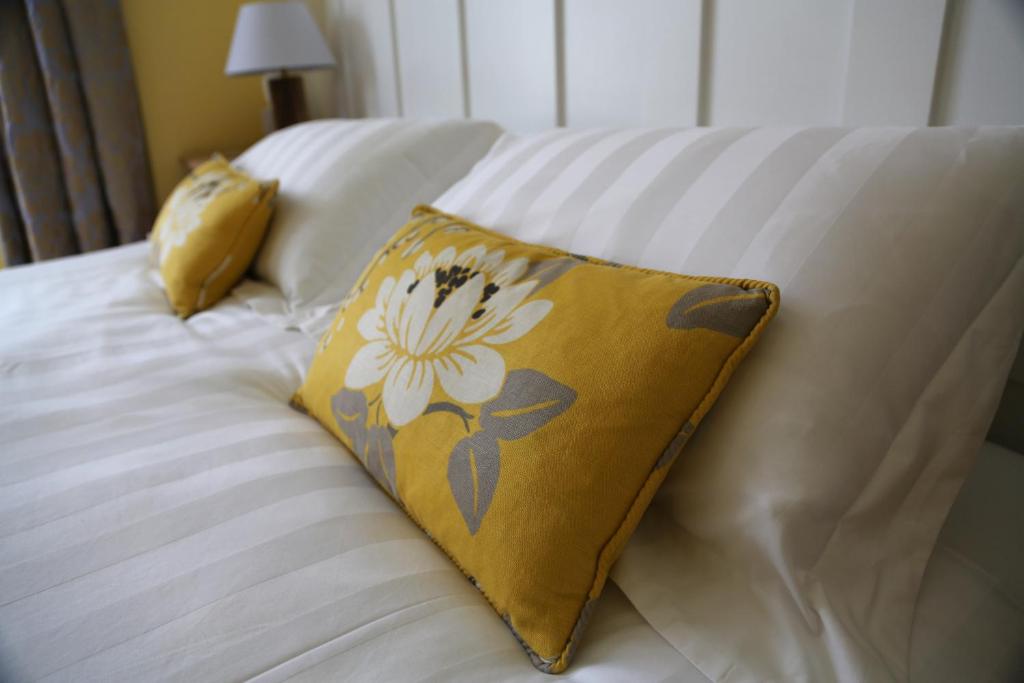 a bed with a yellow pillow with a flower on it at Holly Tree House in Cowes