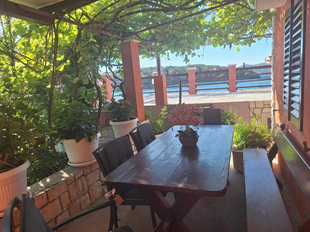 een houten tafel en stoelen op een patio met planten bij 2 bedrooms house with sea view furnished garden and wifi at Potirna in Vela Luka