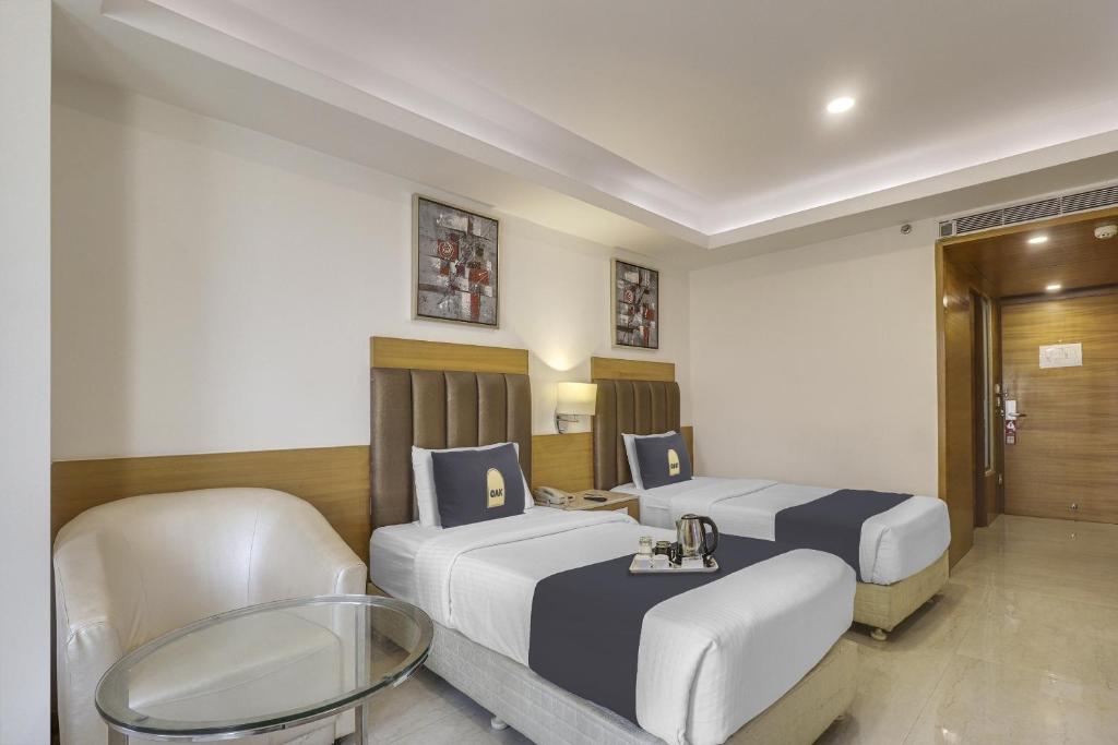 Cette chambre comprend 2 lits et une table. dans l'établissement Palette - Hotel chennai le palace, à Chennai