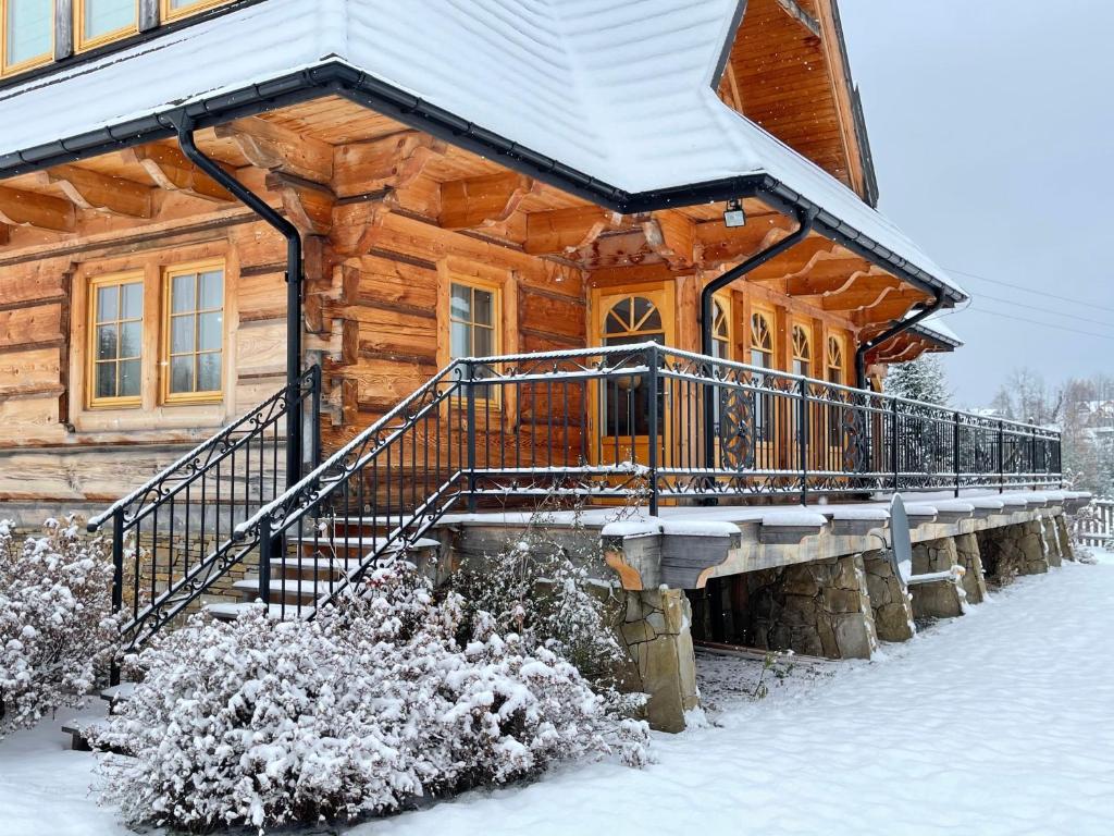 a log cabin with snow on the stairs at Villa z widokiem na Giewont in Kościelisko