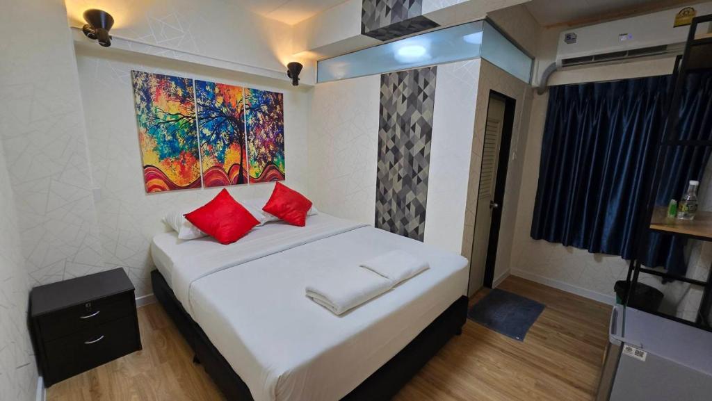 a bedroom with a bed with red pillows and a painting at Khaosan Art Hotel - SHA Plus Certified in Bangkok