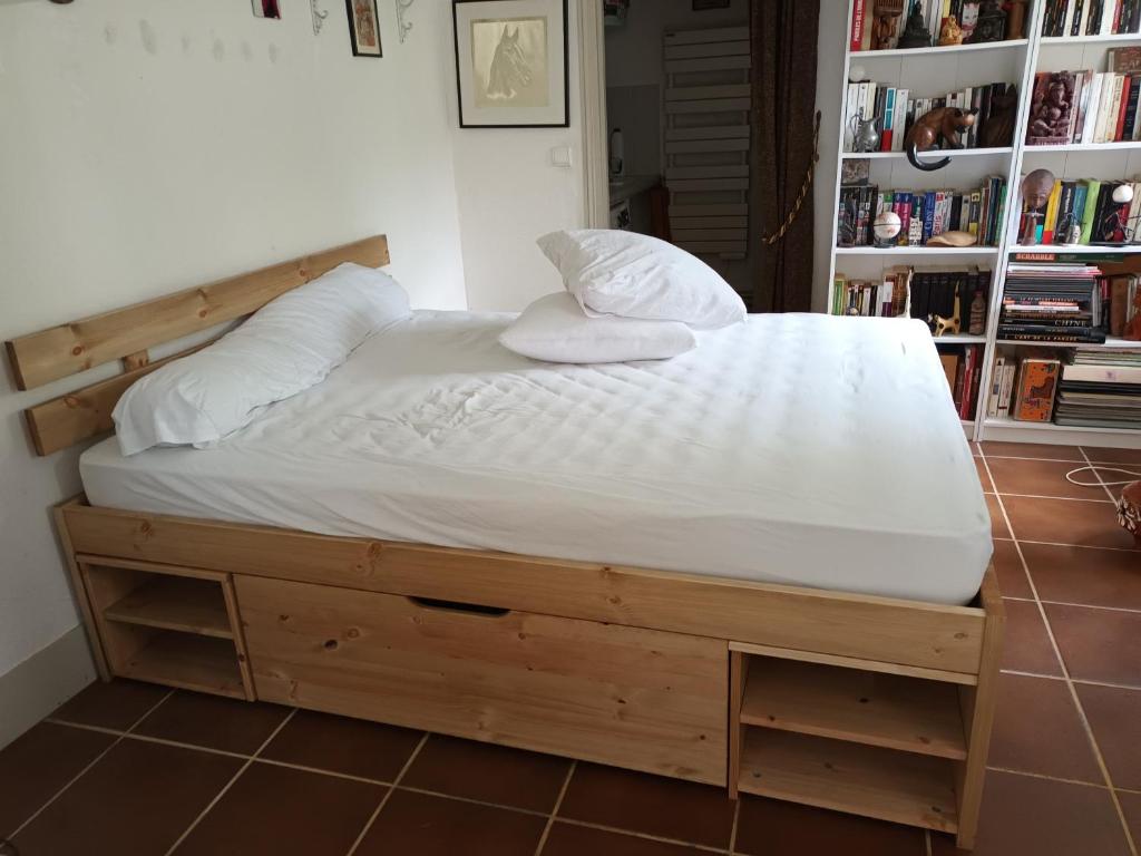 een bed met een houten bedframe in een kamer bij Annexe indépendante in Bourron-Marlotte