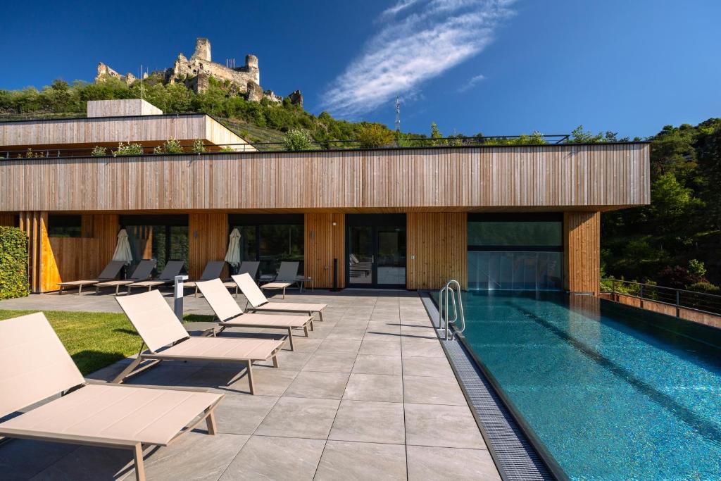 een zwembad met ligstoelen en een gebouw met een kasteel bij Weinhaus Nigl - Hotel, Restaurant und Spa in Senftenberg
