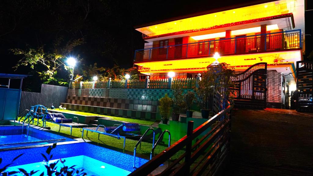 a swimming pool in front of a building at night at Arabian Nights Munnar in Munnar