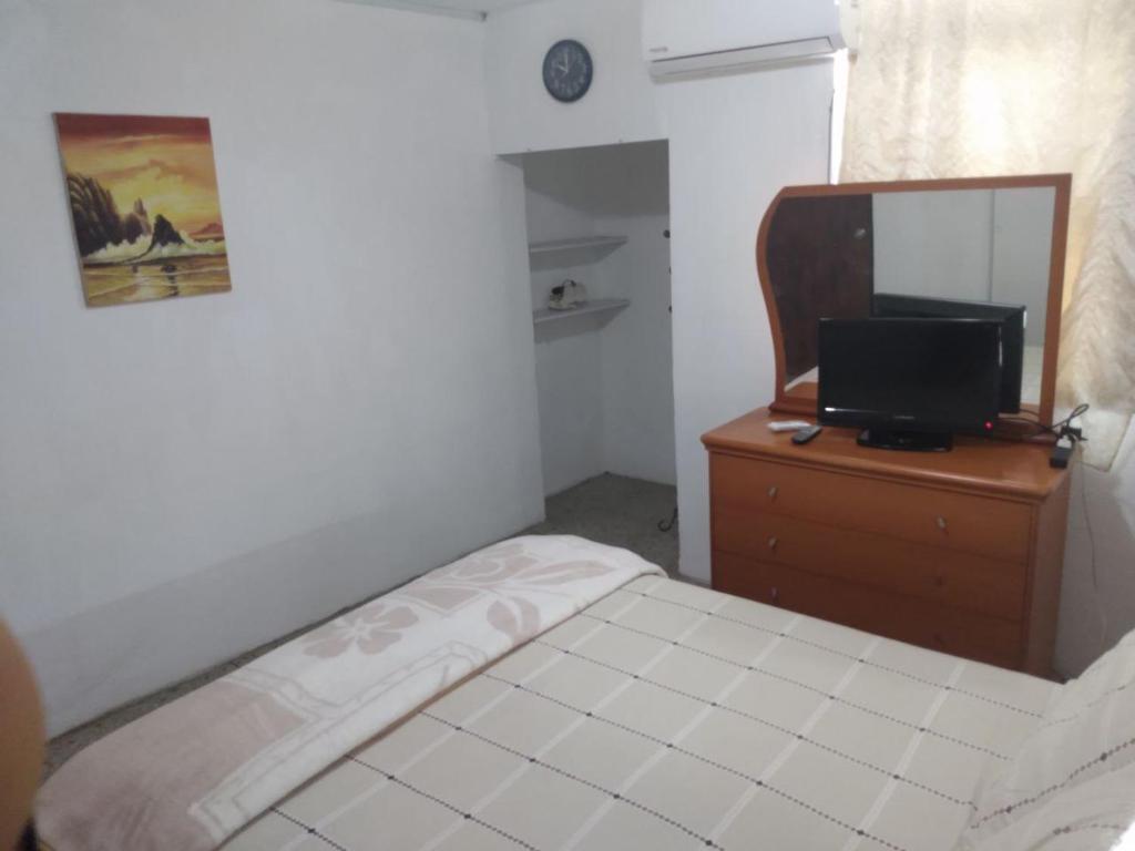a bedroom with a bed and a dresser with a mirror at Habitación para una persona in Puerto La Cruz