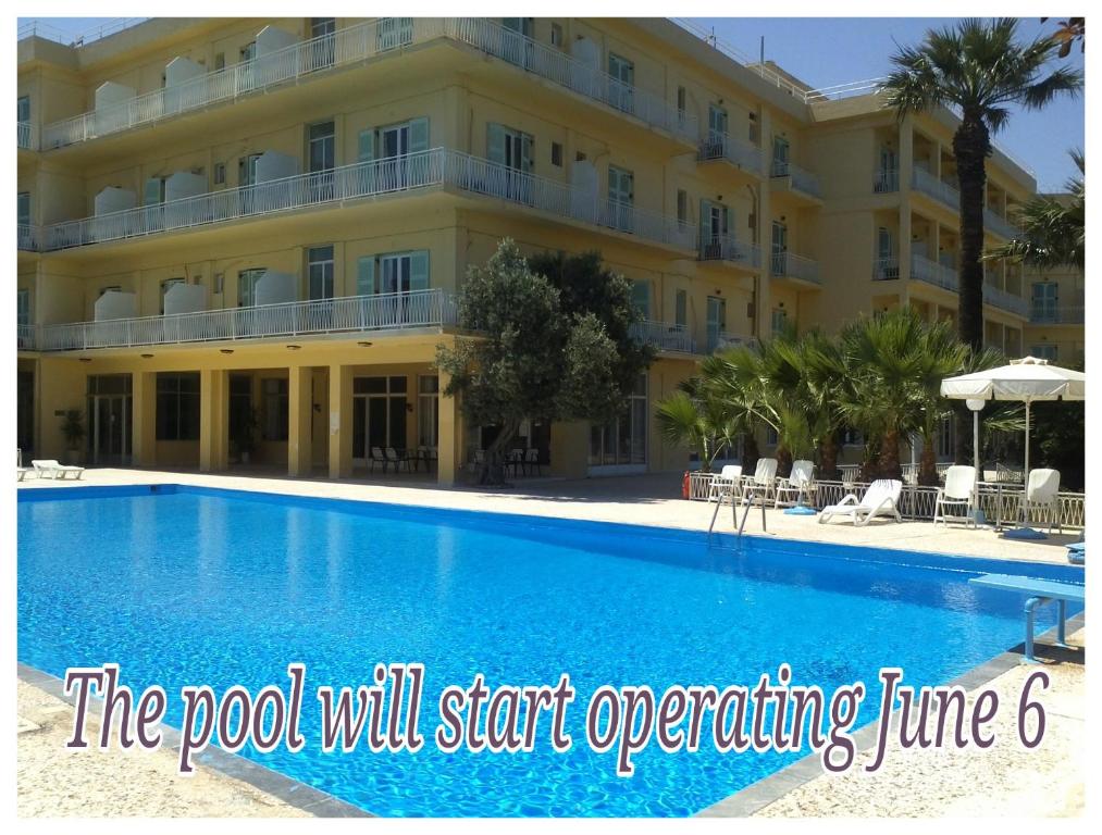 a hotel with a swimming pool in front of a building at Nireus Hotel in Nea Makri
