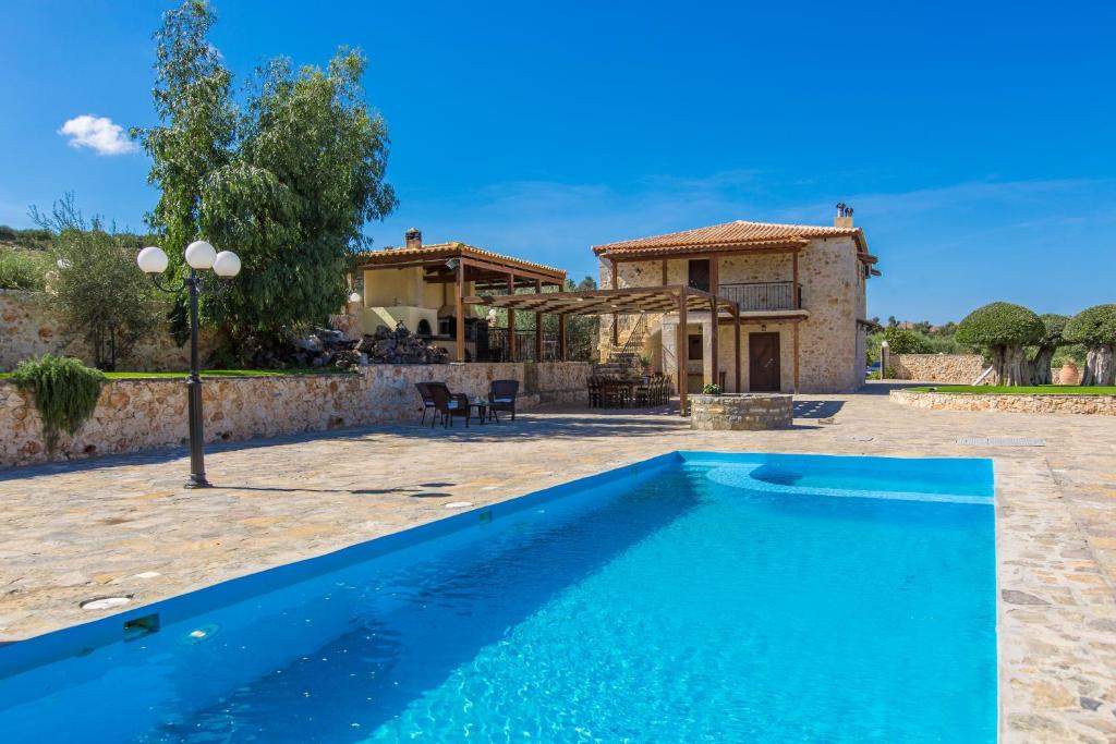 a blue swimming pool in front of a house at Nestor Villa, with Private Pool & Absolute Privacy in Roumelí