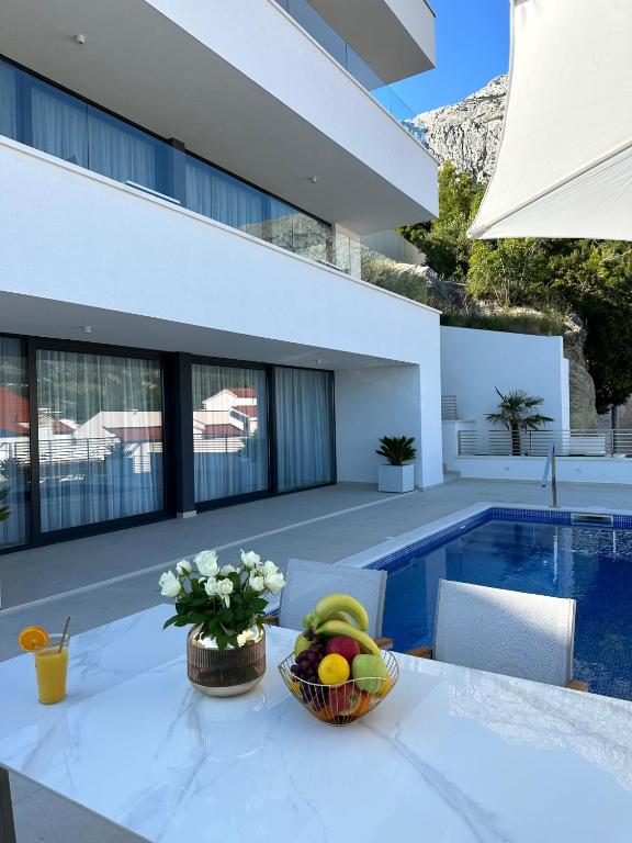 a bowl of fruit on a table next to a swimming pool at Villa Apartment Danny in Baška Voda