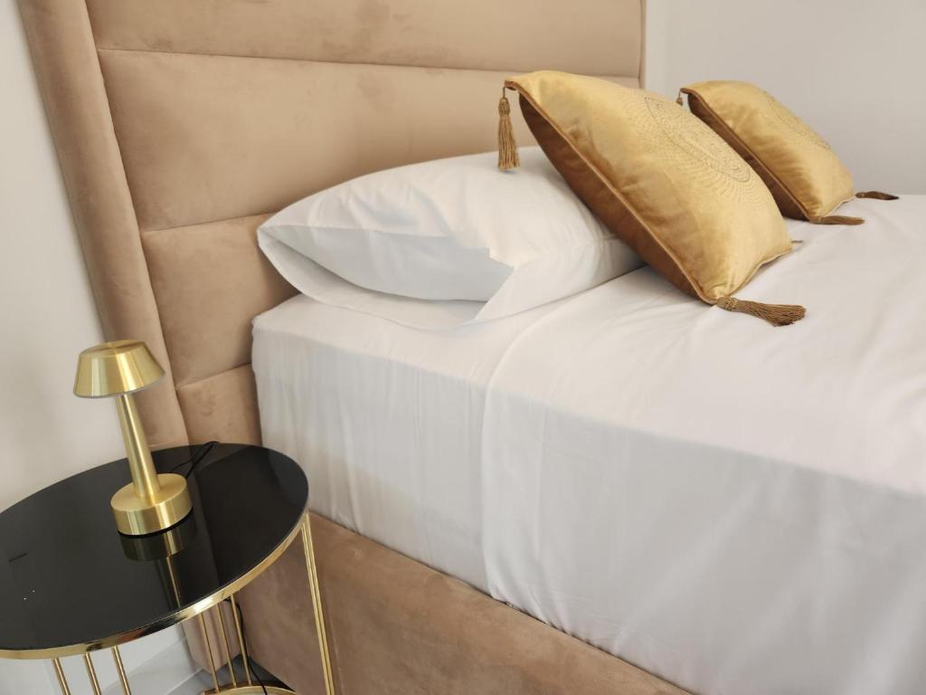 un letto con lenzuola e cuscini bianchi e un tavolino di Villa Apartment Danny a Baška Voda