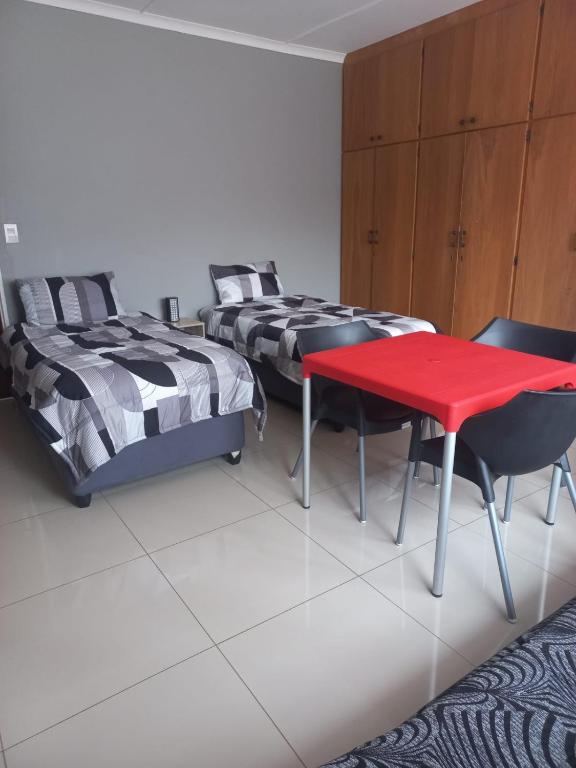 a bedroom with two beds and a red table at Dafel street Guesthouse in Piet Retief