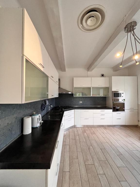 une cuisine avec des armoires blanches et des comptoirs noirs dans l'établissement Cottage indipendente con piscina privata, à Masi San Giacomo