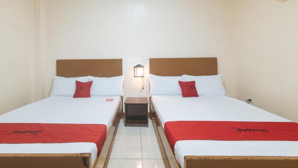two beds in a hotel room with red pillows at RedDoorz at Elegance Guest House near NAIA T3 in Manila