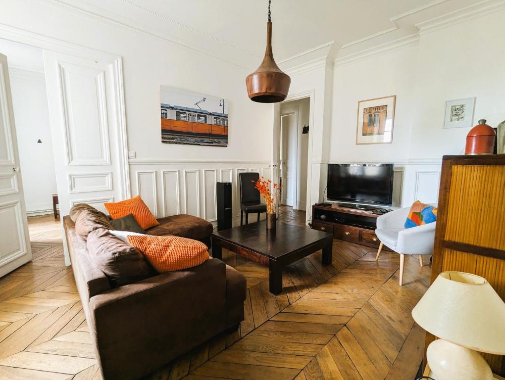 un salon avec un canapé et une télévision dans l'établissement Appartement typique et confortable - Voltaire, à Paris