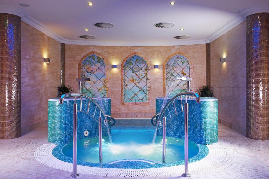 a spa room with a plunge pool and stained glass windows at Retro Riverside Wellness Resort in Karlovy Vary