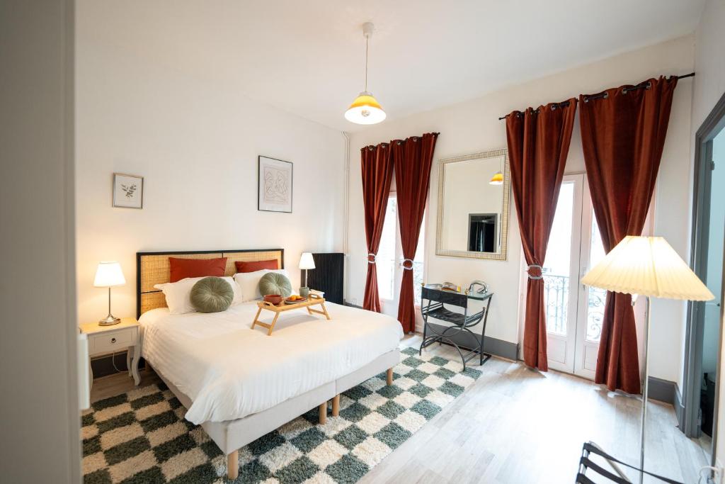 a bedroom with a white bed with red curtains at Villa Vichéia - Appartement 13 in Vichy