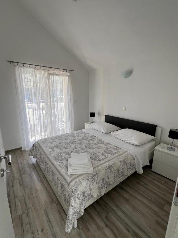 Un dormitorio blanco con una cama grande y una ventana en Sunce apartments en Grebaštica
