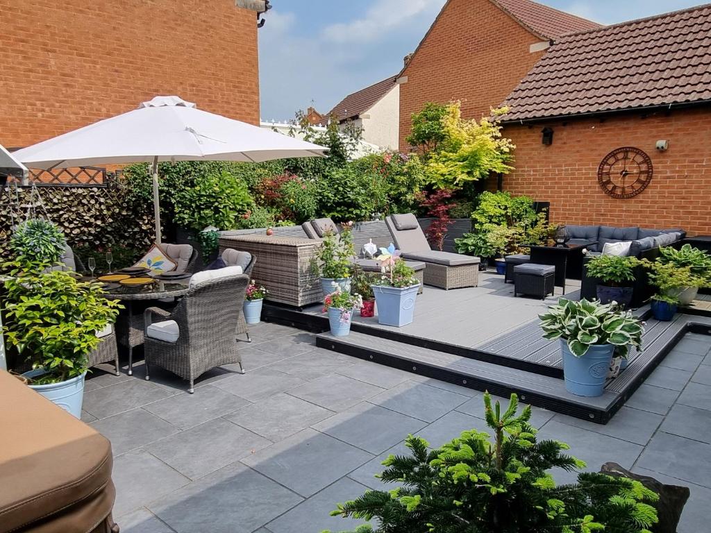 a patio with chairs and an umbrella and plants at Dungarvon House B&B, Exclusive Bookings Only, Hot tub, Garden & Summerhouse, EV Point in Weston-super-Mare