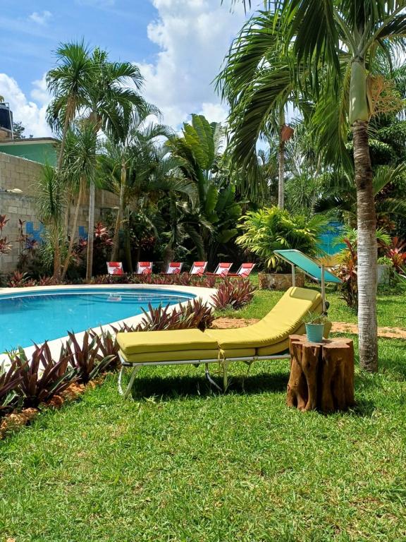 a yellow bench next to a pool with palm trees at GREEN PARADISE LEONA VICARIO in Leona Vicario