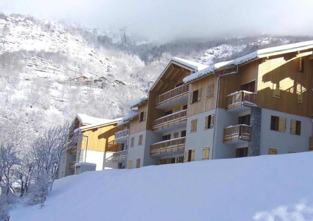 ein Gebäude im Schnee mit einem Berg im Hintergrund in der Unterkunft Résidence Orelle 3 vallées by Resid&Co in Orelle