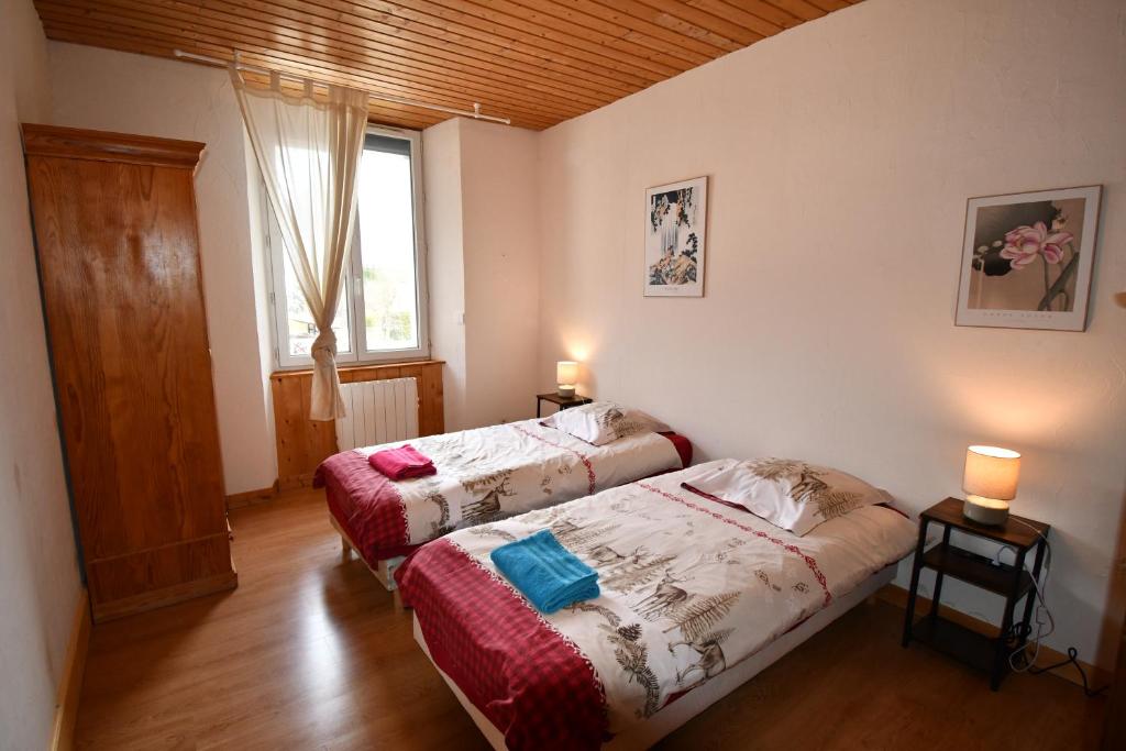 two beds in a room with two lamps and a window at Villa Lutel in Le Bourg-dʼOisans