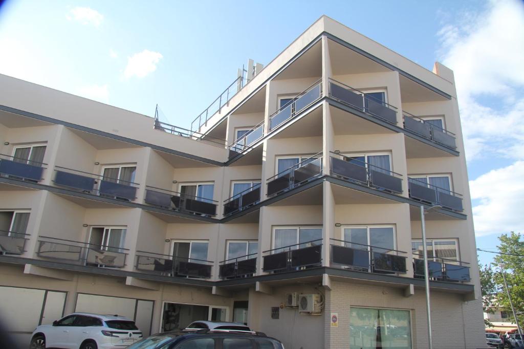 ein Apartmenthaus mit Balkonen und Autos, die vor dem Haus geparkt sind in der Unterkunft Aparthotel Els Molins in Roses