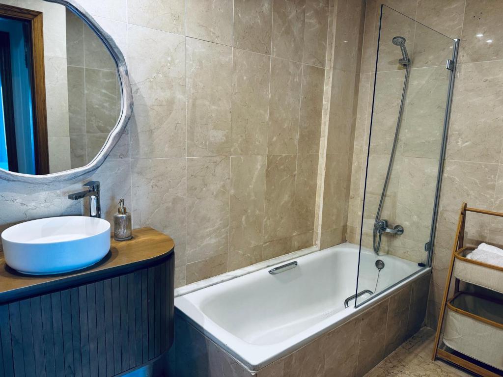 een badkamer met een bad, een wastafel en een spiegel bij La Gavina Loft Xàbia & ARCADE in Jávea