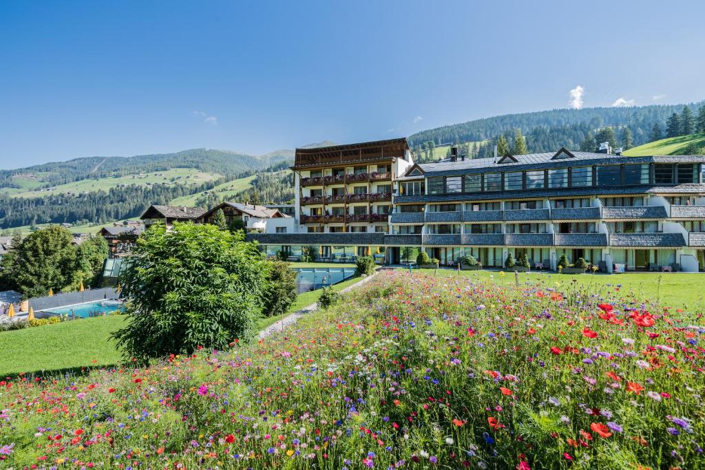 a hotel with a field of flowers in the foreground at Family Resort Rainer in Sesto