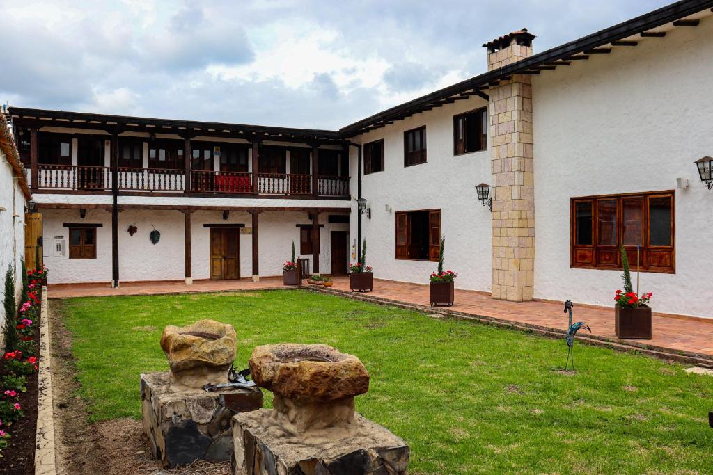 ein Haus mit zwei Steinstatuen in einem Hof in der Unterkunft Casona Quesada in Suesca