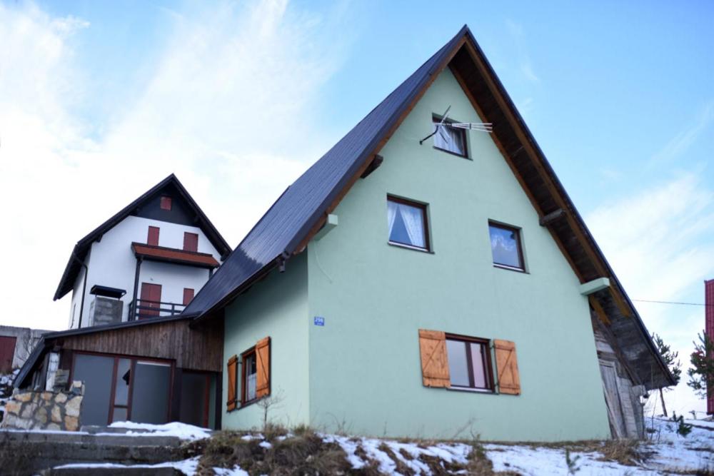 una casa blanca con techo de gambrel en Brano, en Kupres