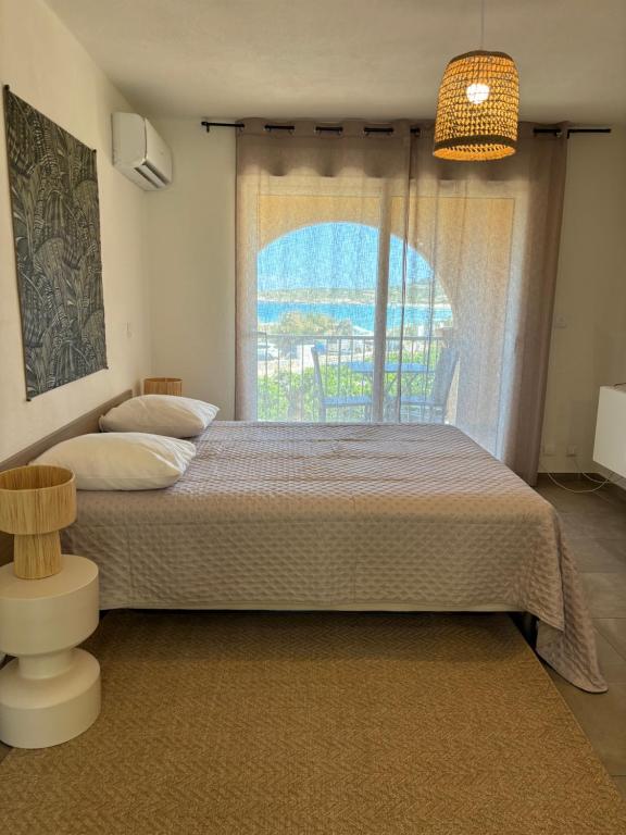 1 dormitorio con 1 cama grande y ventana en Studio pieds dans l'eau, en Algajola