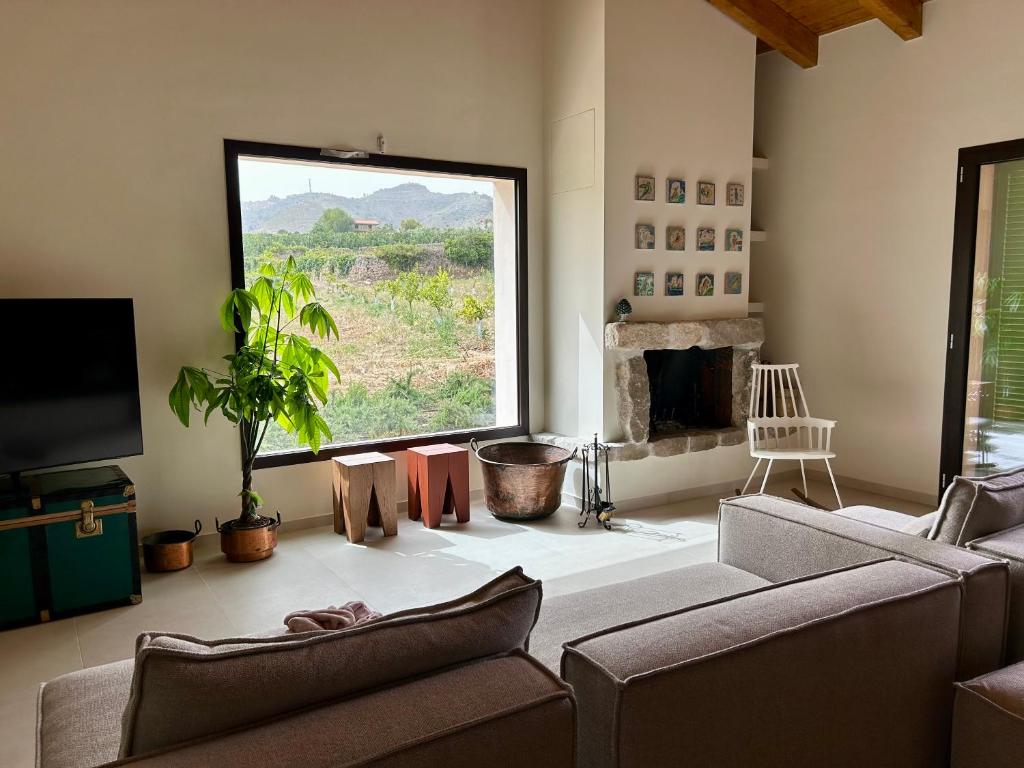 a living room with two couches and a large window at Tenuta Coco in Centuripe