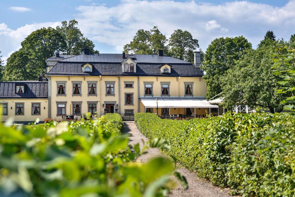 une grande maison blanche avec un toit noir dans l'établissement Hennickehammars Herrgård, à Filipstad