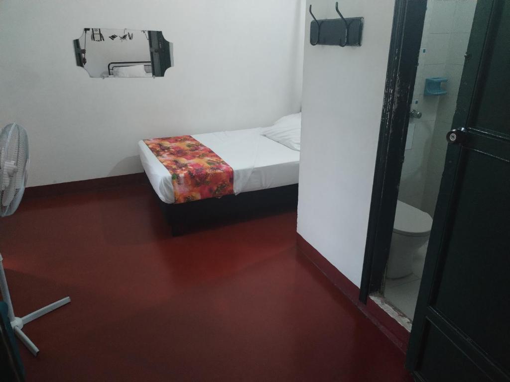 een kleine kamer met een bed en een spiegel bij Hostel La Casona 1859 in Guaduas