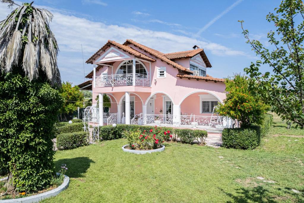 a pink house with a balcony in a yard at Villa Regina By The Sea in Epanomi