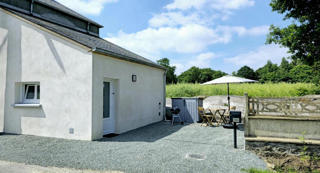 a white building with a table and an umbrella at Maison 4 personnes - Louargat in Louargat