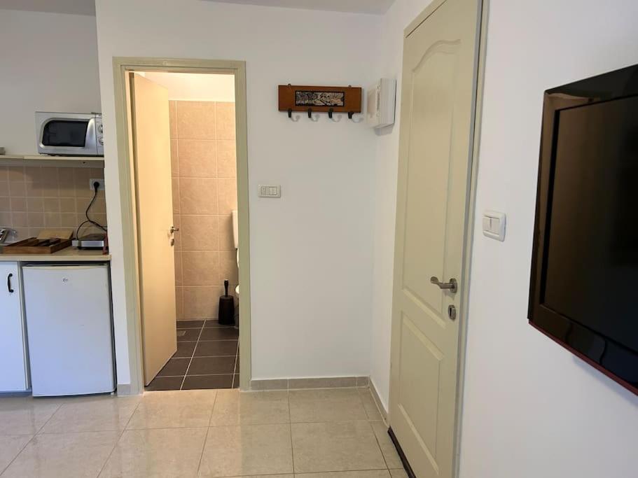 a room with a kitchen and a door with a television at נופש איילה in Bnei Yehuda