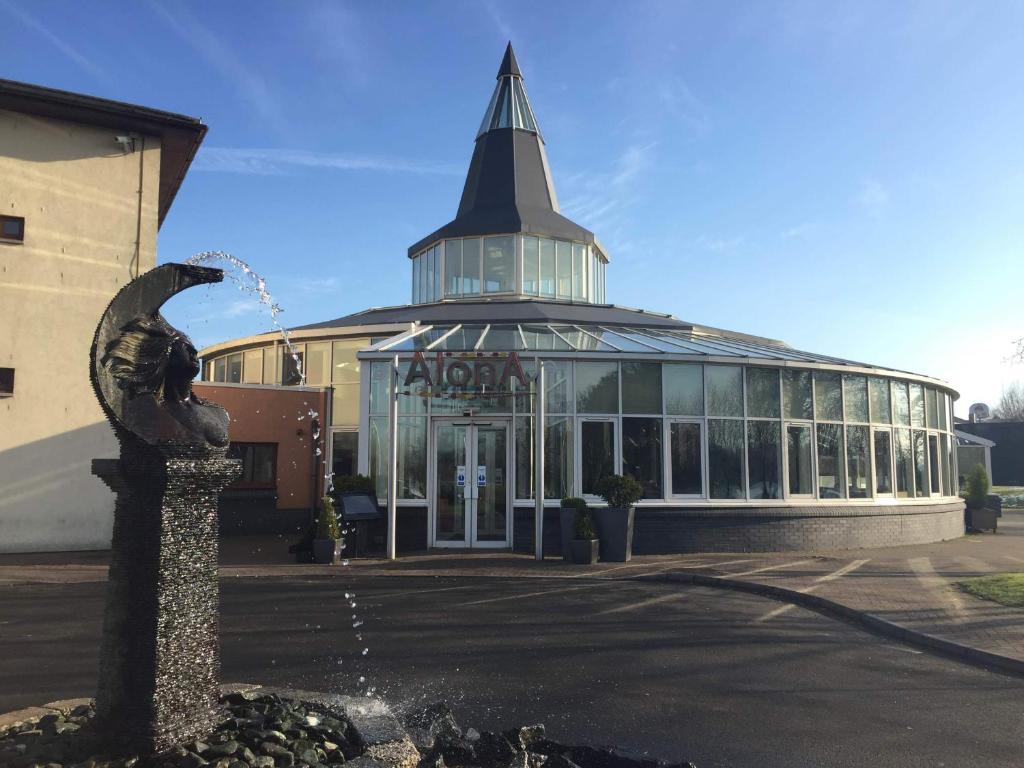 a building with a fountain in front of it at Alona Hotel in Motherwell