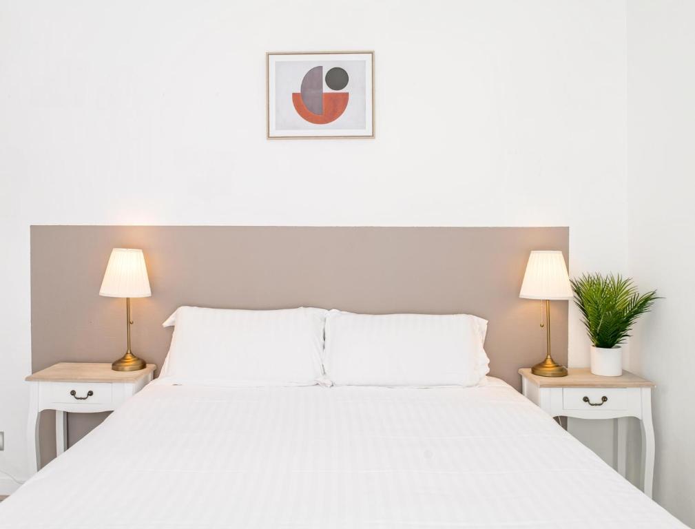 a bedroom with a white bed with two lamps at Villa Vichéia - Appartement 2 in Vichy