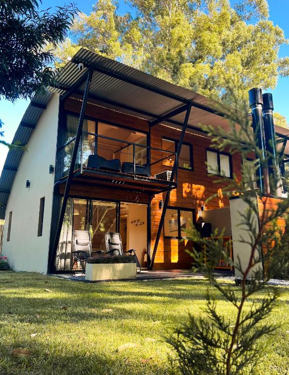 a house with a balcony and some chairs in a yard at Cabañas Sol de Abril in Mar del Plata