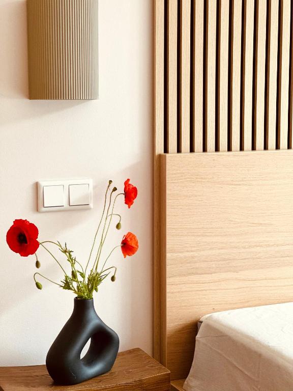 a black vase with red flowers sitting on a table at Yutori - Apartment in Malchow