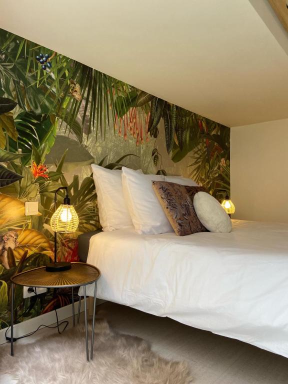 - une chambre avec un lit blanc et un papier peint tropical dans l'établissement La Sellerie - Loft de luxe au cœur d'Angers, à Angers