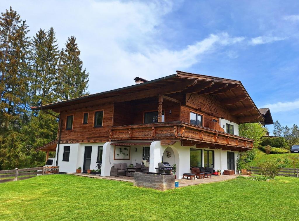 ein großes Holzhaus auf einem Grasfeld in der Unterkunft Ferienwohnung Kurz in Kössen