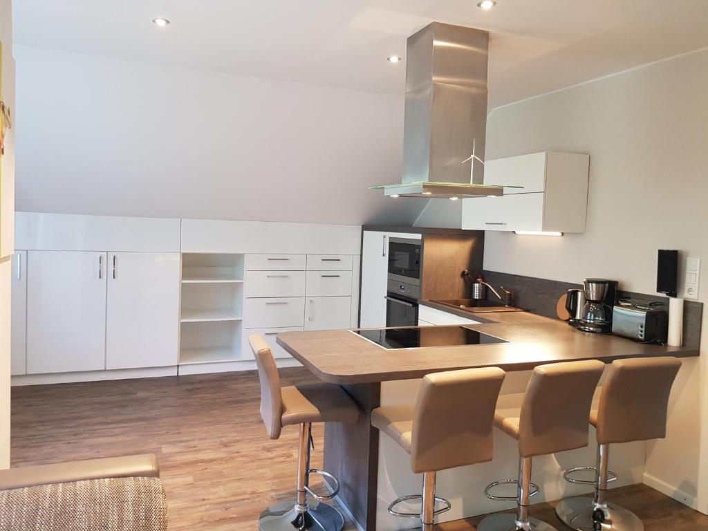 a kitchen with white cabinets and a island with bar stools at Soltbargen in Husum