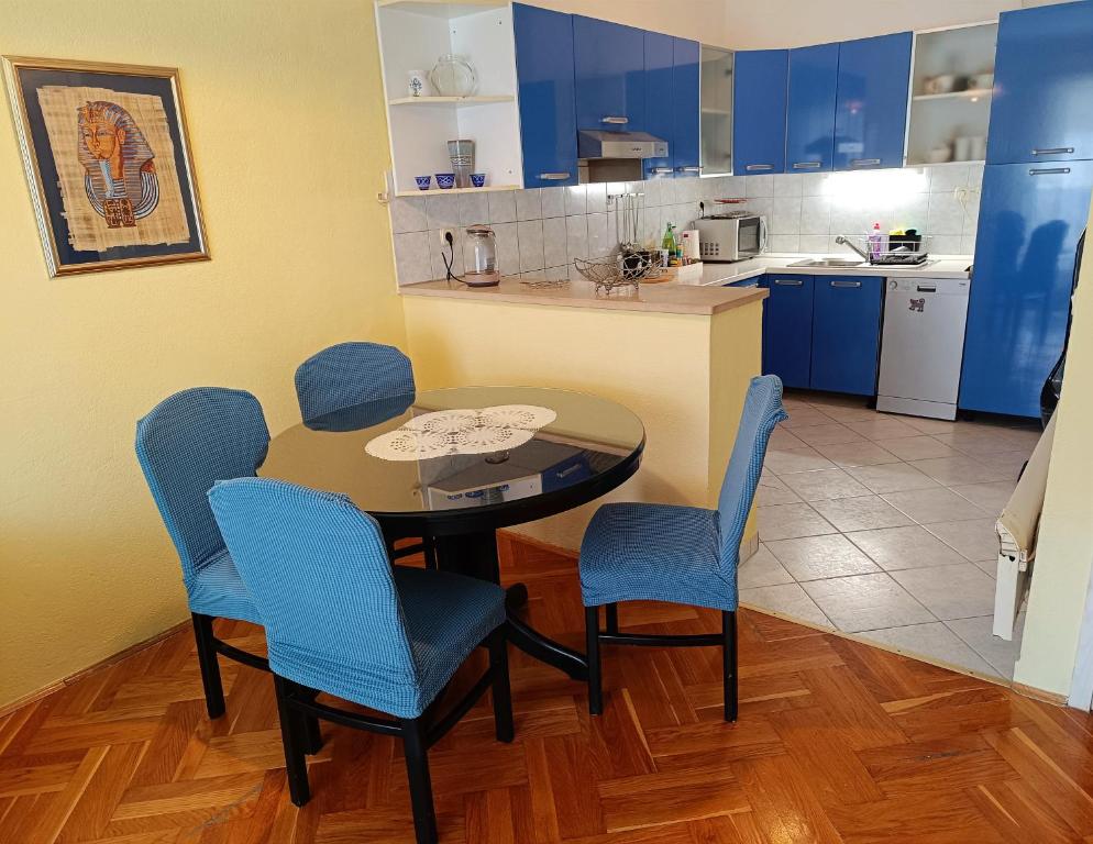 eine Küche mit einem Tisch und blauen Stühlen in einem Zimmer in der Unterkunft Apartment near beach with free parking in Kaštela